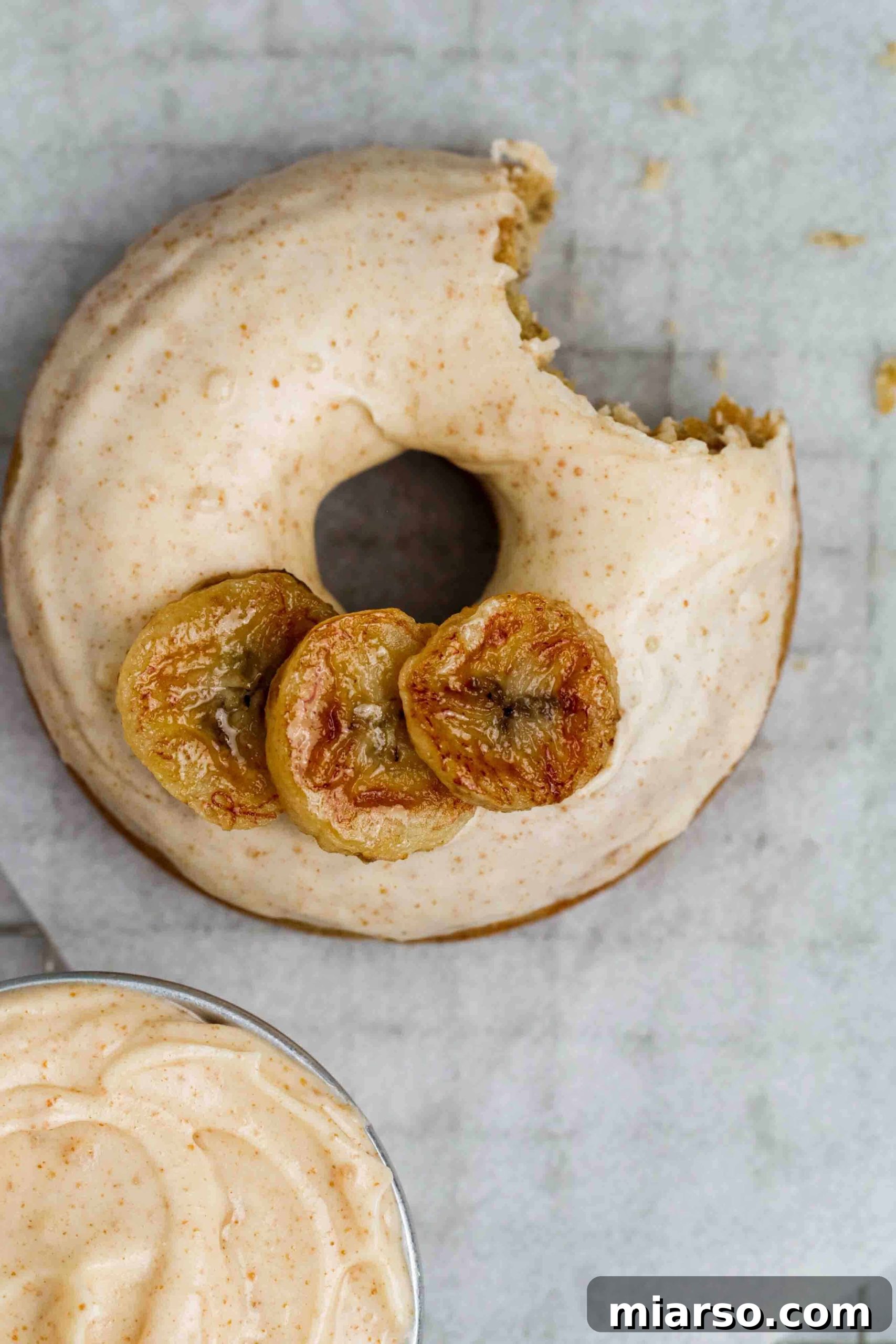 Overhead shot of a delicious banana donut with a bite taken out, revealing its soft interior and the glaze.
