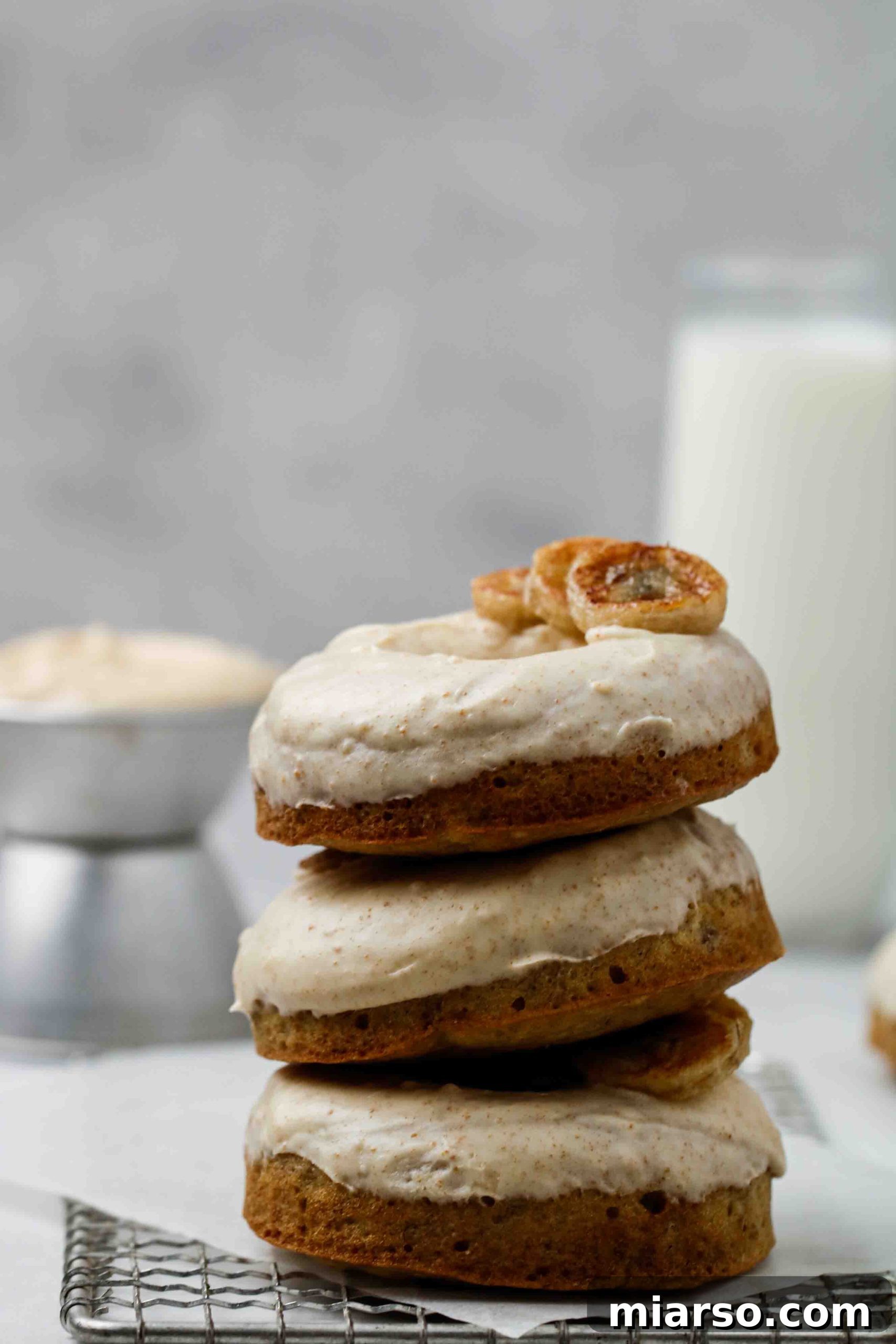 A tall stack of perfectly golden-brown baked banana bread donuts, ready for glazing.