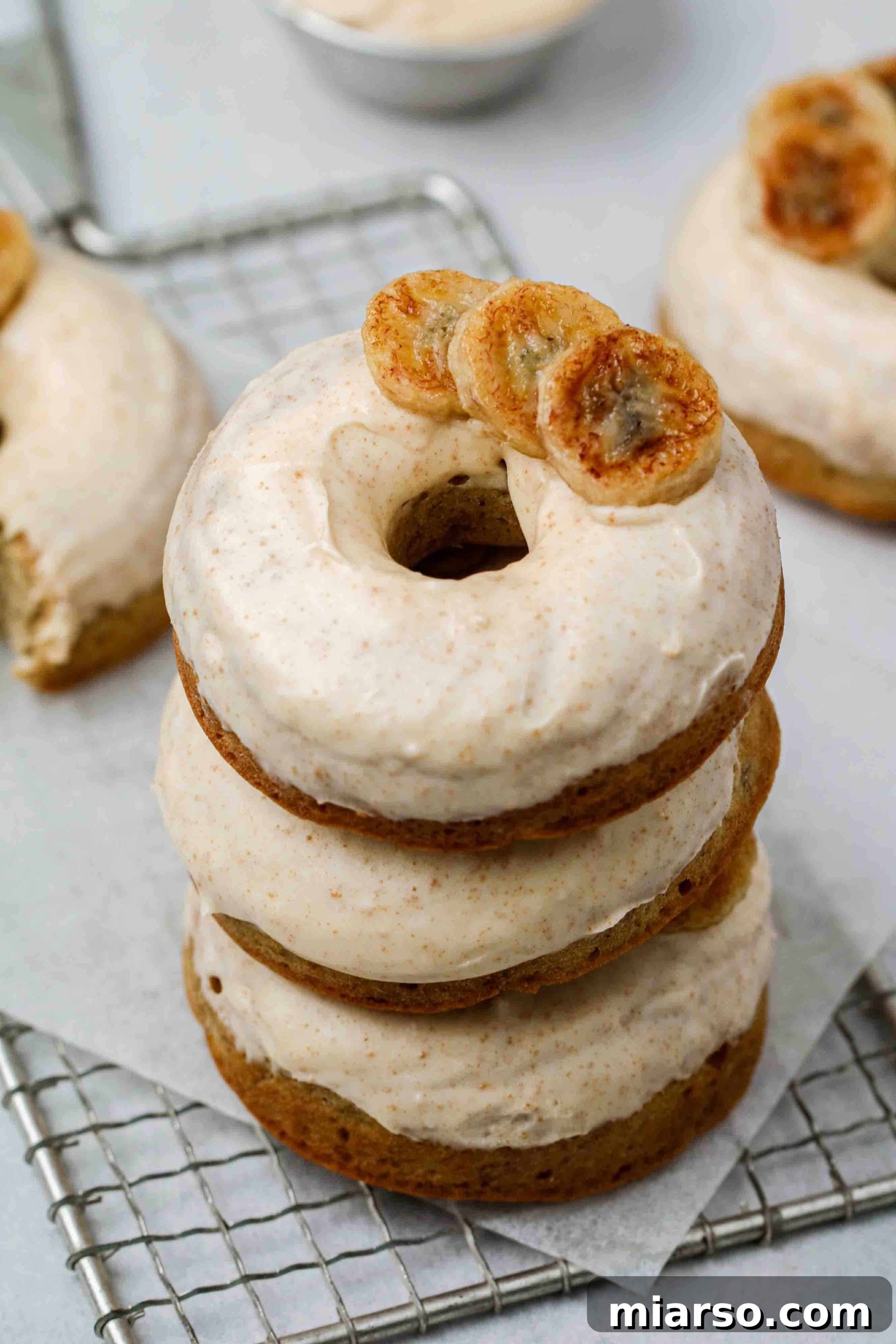 Stack of five perfectly baked banana donuts with a generous drizzle of brown butter glaze