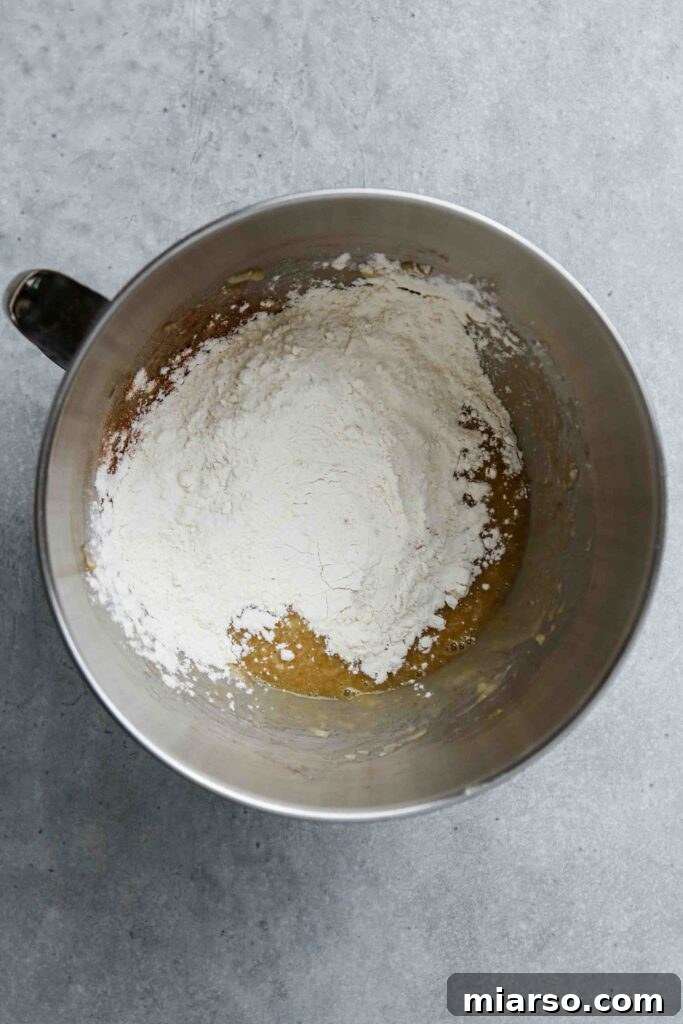 Donut batter being carefully poured into a greased donut pan, preparing for baking.