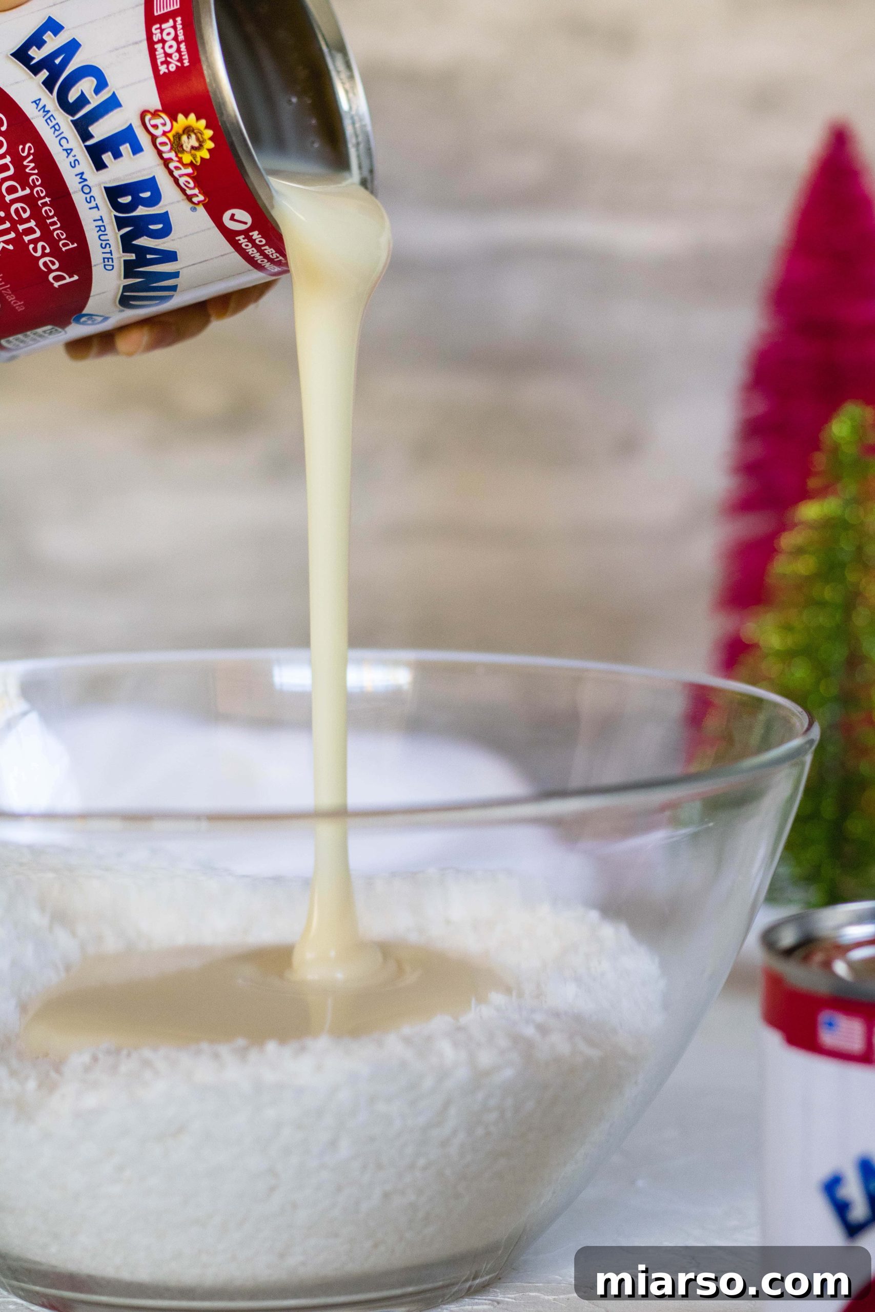 Pouring sweetened condensed milk into coconut flakes for no bake coconut balls