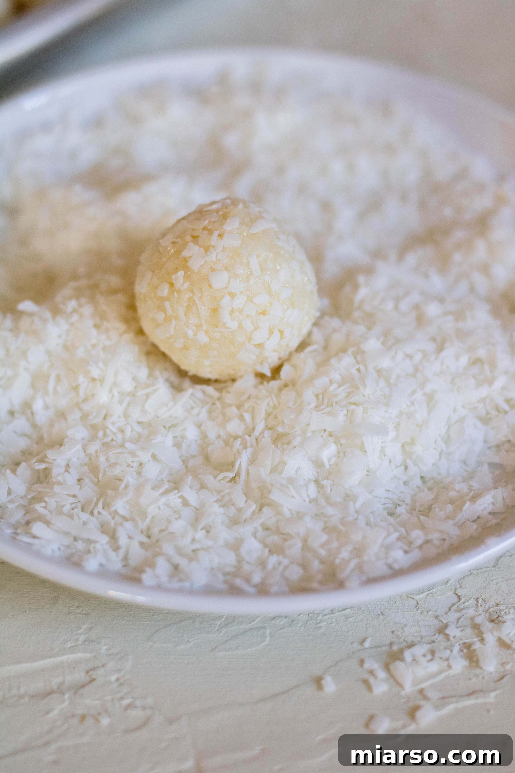 Coating the no bake coconut balls with extra shredded coconut