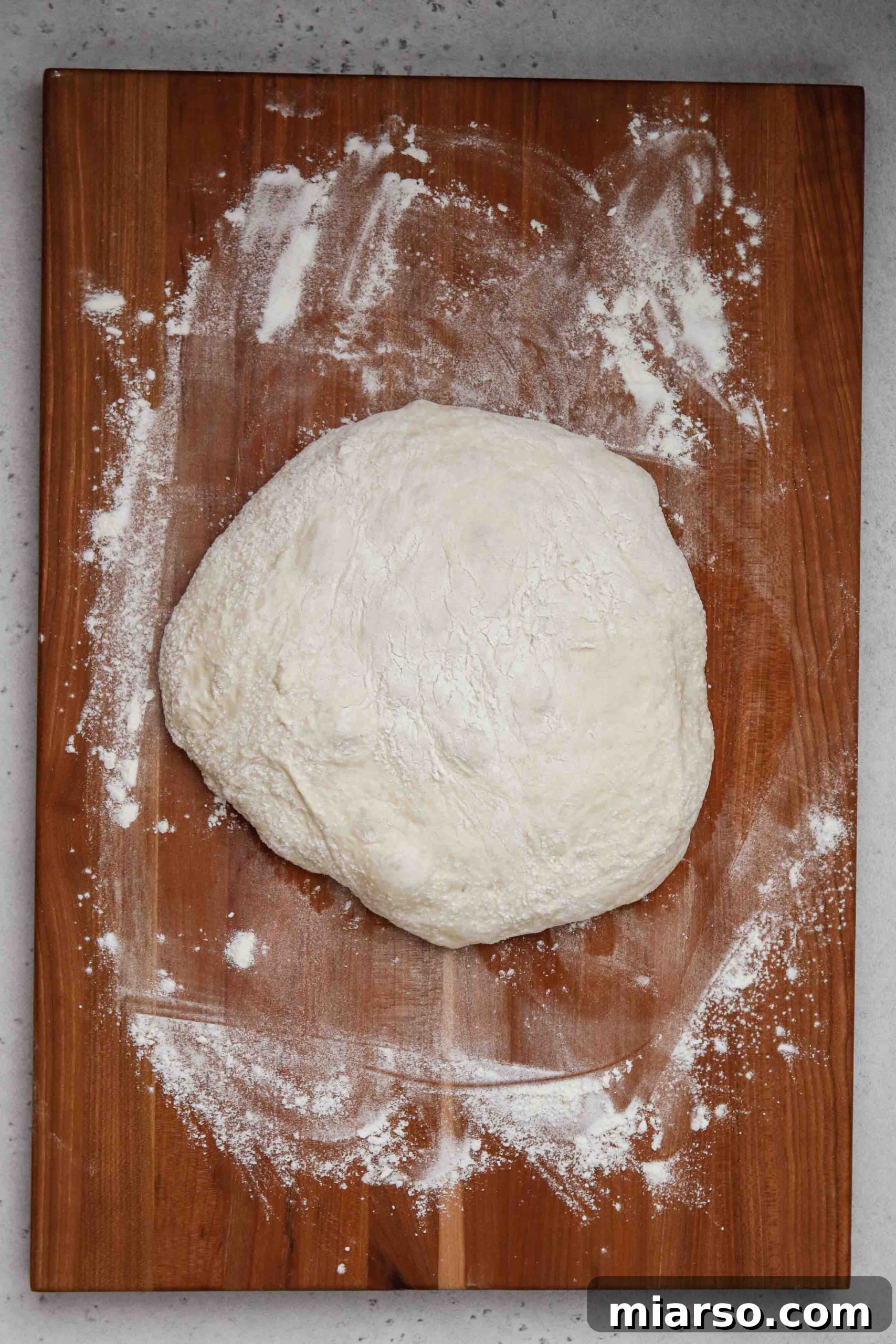 Homemade pizza dough resting in an oiled bowl, covered with plastic wrap, ready for storage.