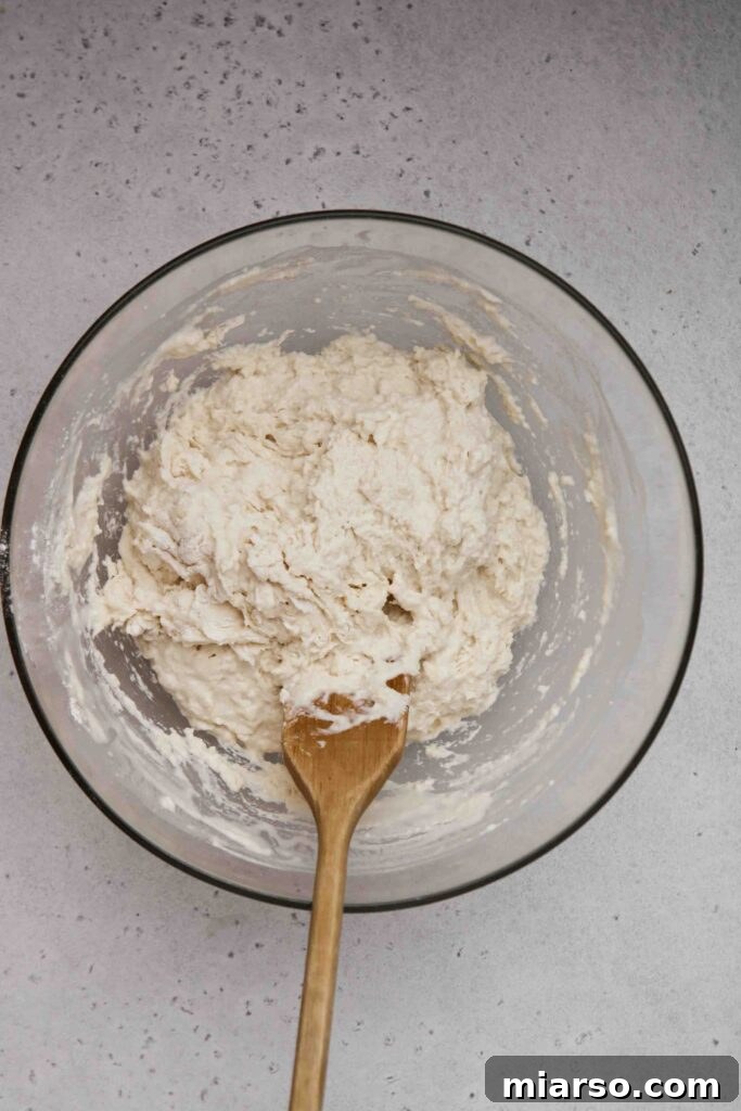 Close-up of the shaggy, mixed no-knead pizza dough in a bowl.
