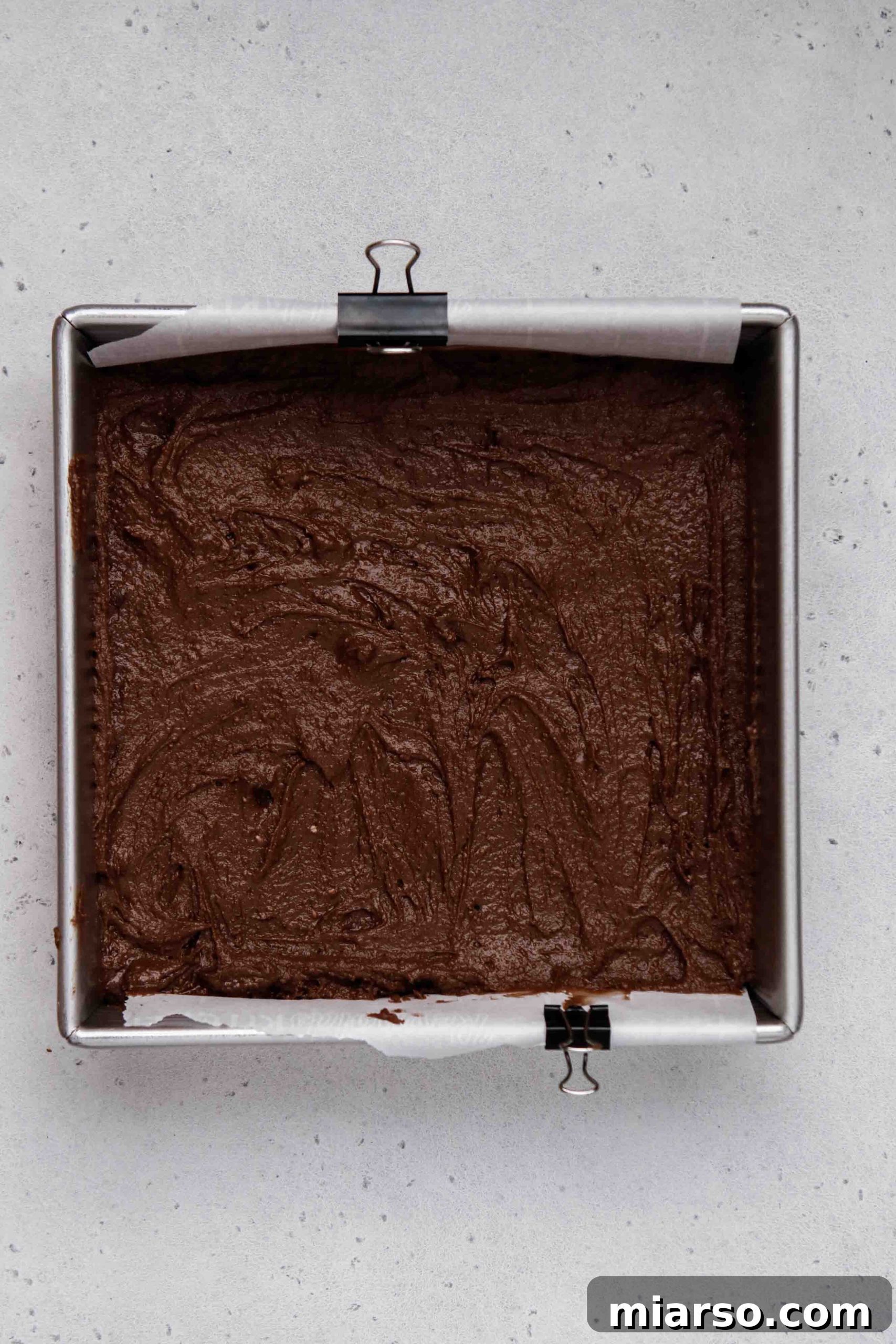 Brownie mix batter being poured into a baking pan