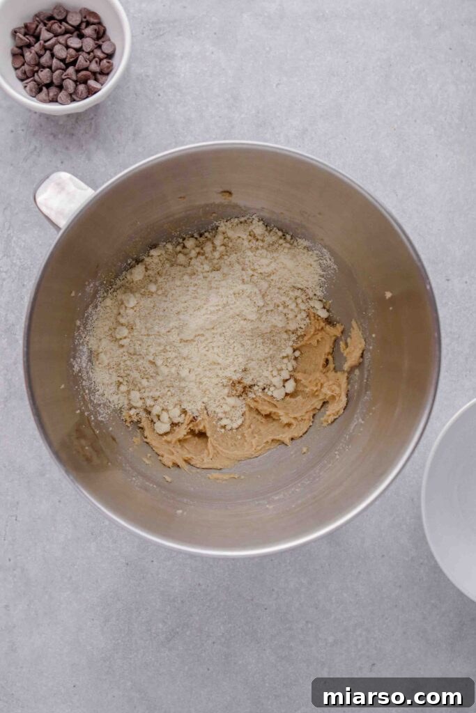 Adding almond flour to the creamed butter mixture.