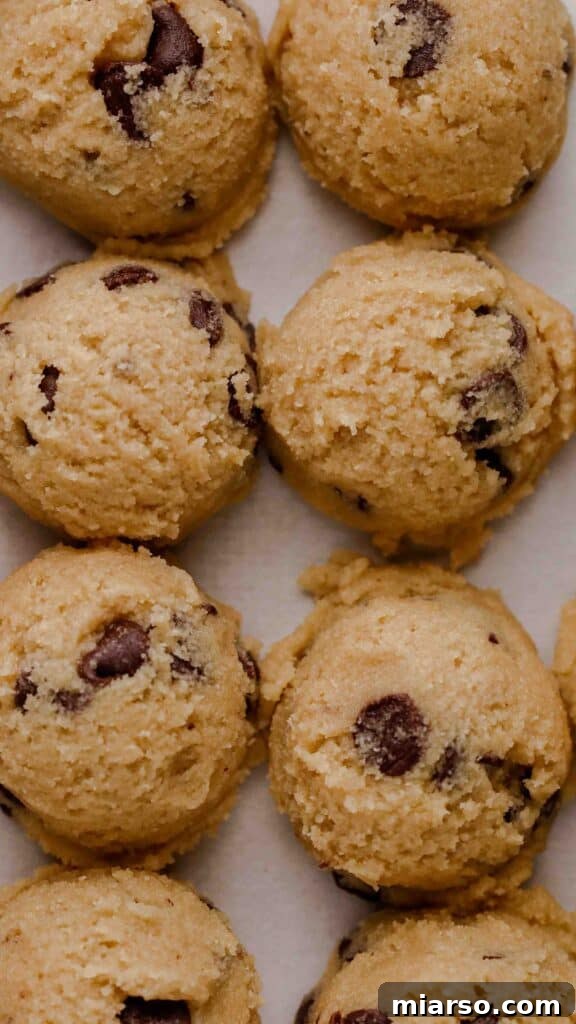 Scooped almond flour cookie dough balls on a baking sheet, ready for chilling.