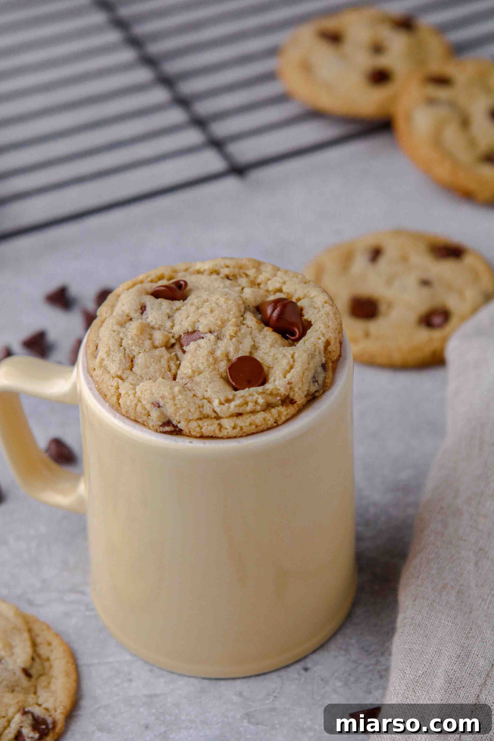 A stack of soft and chewy almond flour chocolate chip cookies on a wire rack.