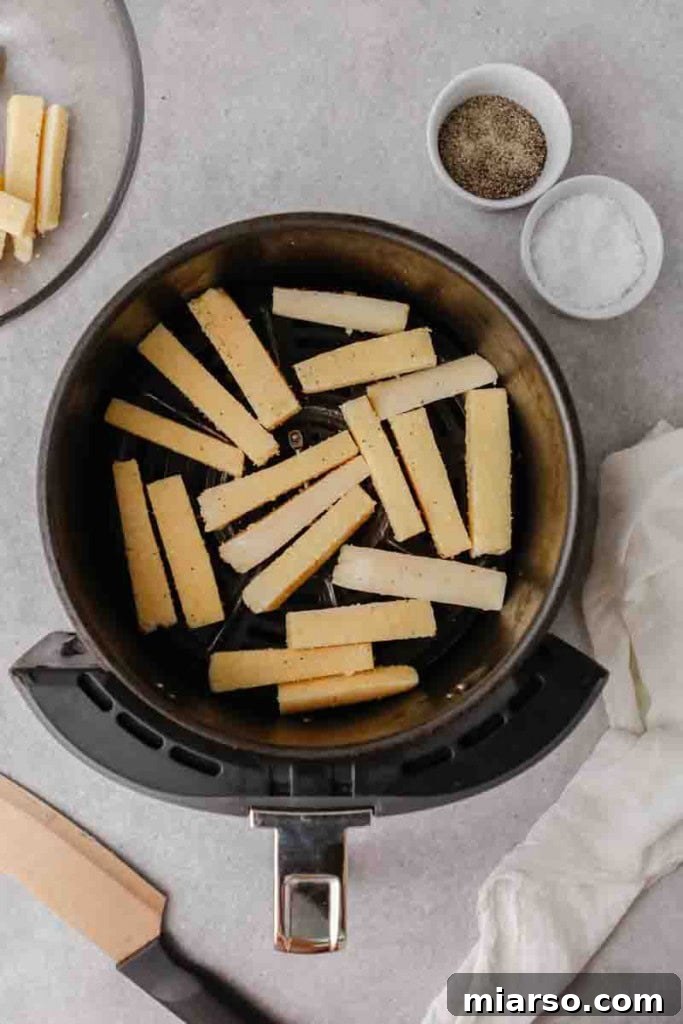Polenta fries arranged in a single layer in an air fryer basket, ready for cooking