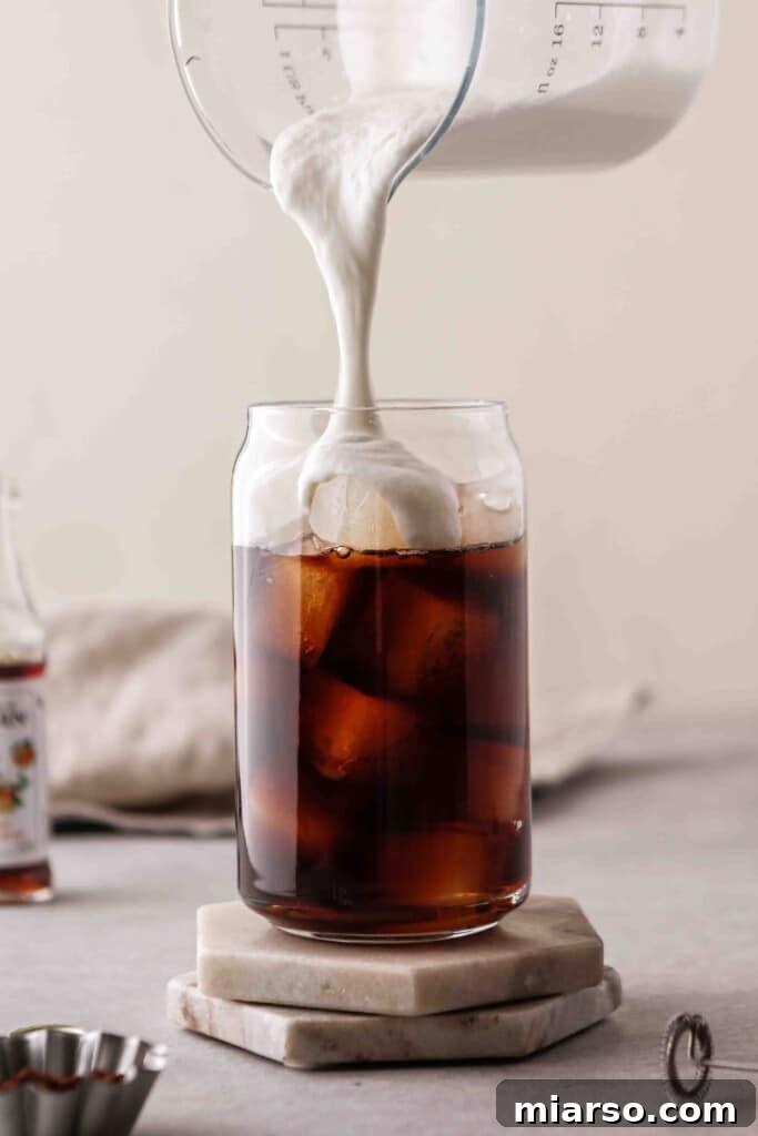 Pouring vanilla sweet cream over cold brew coffee