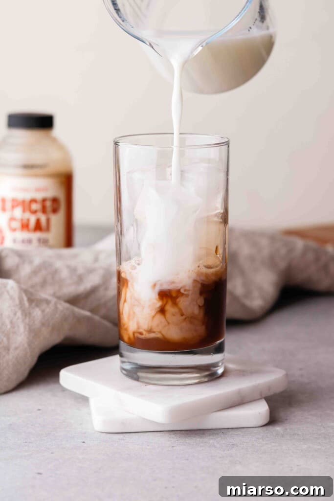 Pouring milk over chai tea concentrate and ice