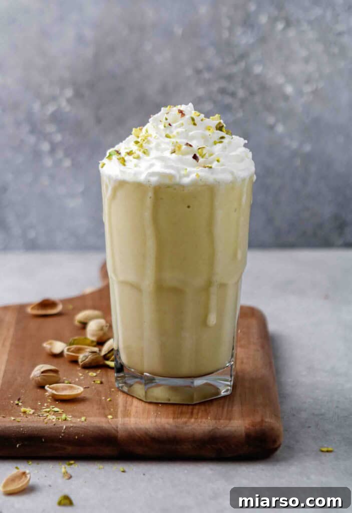 A vibrant green homemade Starbucks Pistachio Frappuccino copycat recipe, topped with whipped cream and chopped pistachios, ready to be enjoyed.