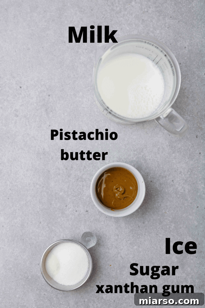 A flat lay of all the essential ingredients needed for a homemade Starbucks pistachio frappuccino copycat recipe, including milk, ice, pistachio butter, and xanthan gum.