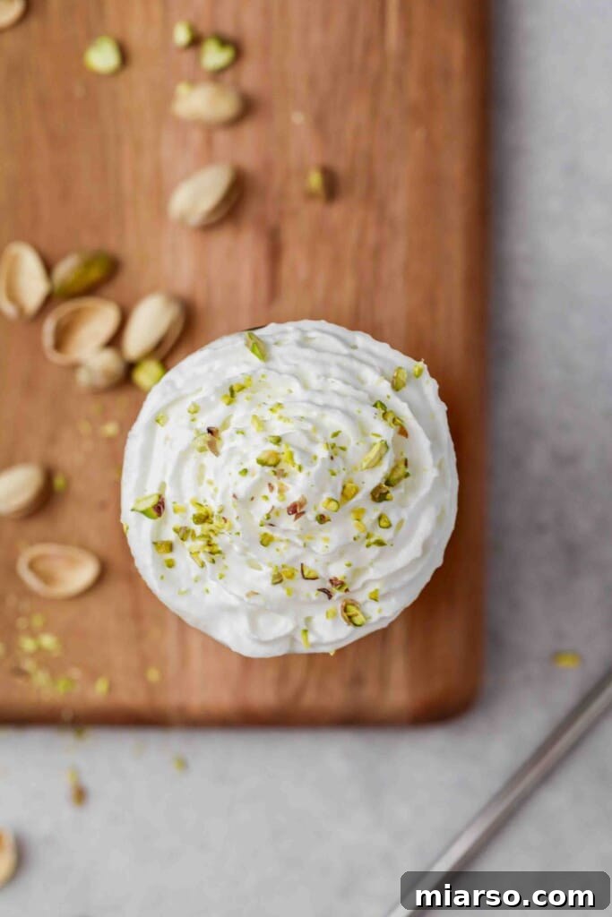 An inviting overhead shot of a homemade pistachio frappuccino, elegantly topped with fluffy whipped cream and a sprinkling of vibrant green chopped pistachios.