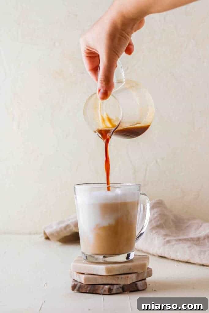 Pouring espresso into steamed milk with vanilla syrup