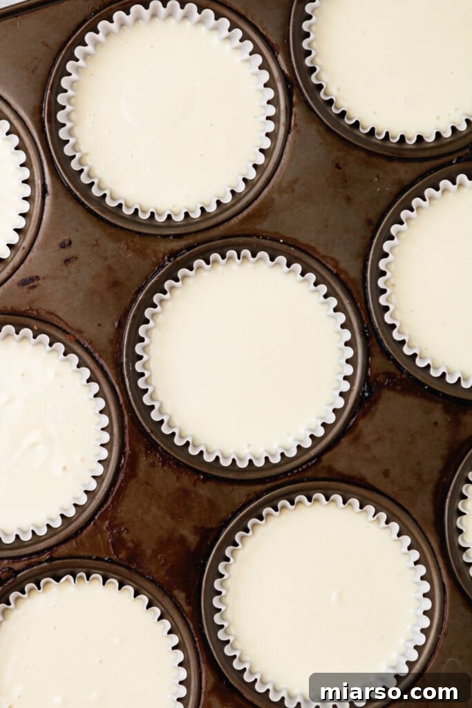 Muffin tin filled with cheesecake batter, ready for baking