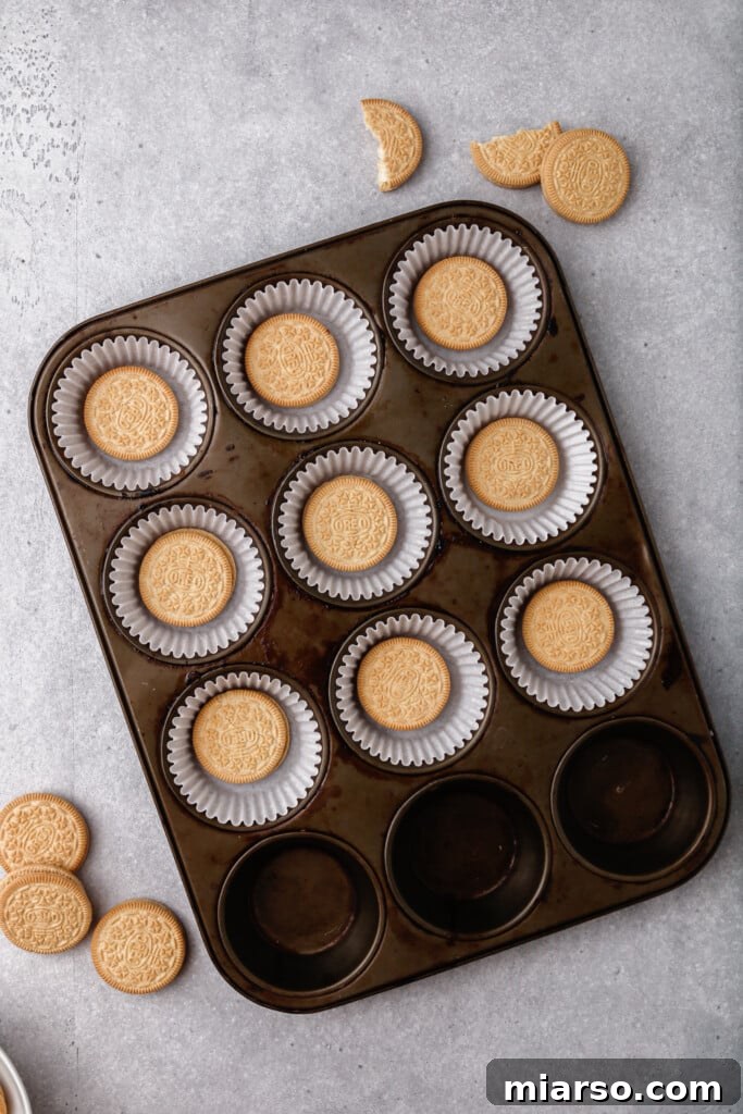 Placing an Oreo cookie into muffin liners for the crust