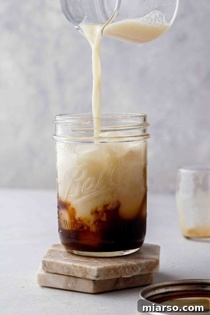 Golden Oat Shaken Espresso 10 Pouring oat milk over shaken espresso and ice