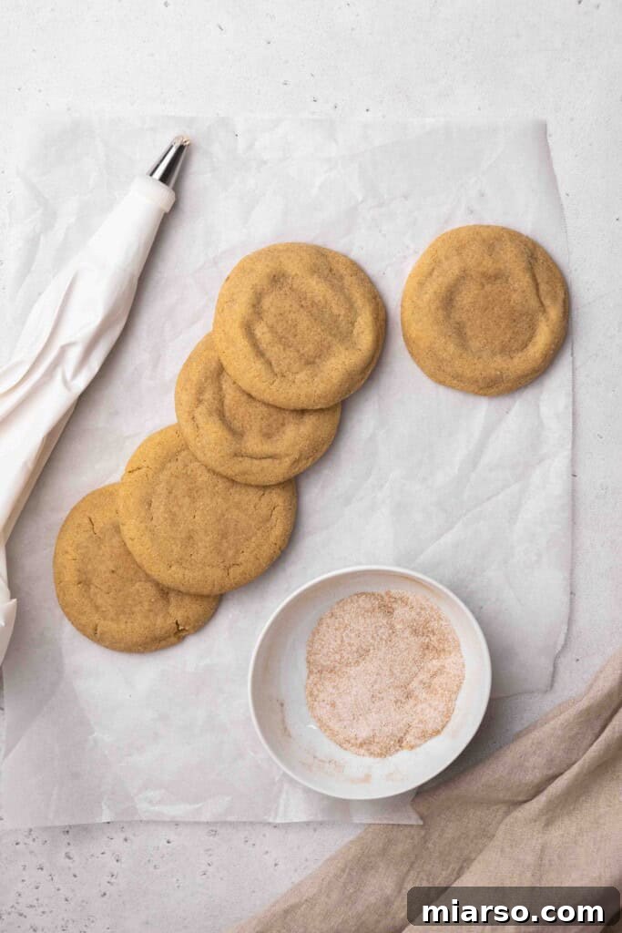 Freshly baked unfrosted cinnamon sugar cookies cooling on a rack, ready for buttercream.