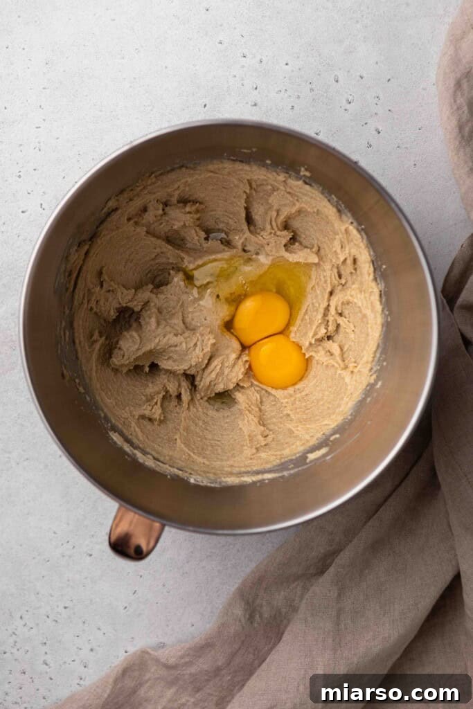 Creamed butter and sugar with eggs being added for the Crumbl Churro Cookie dough.