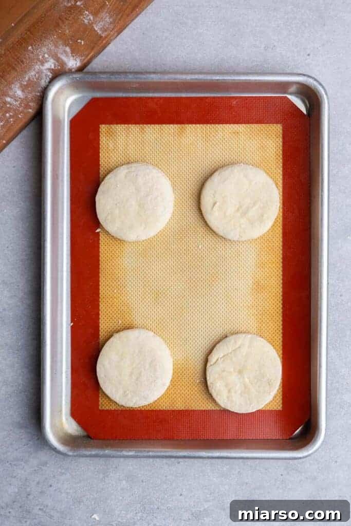 Unbaked biscuits arranged on a parchment-lined baking sheet, ready for the oven.