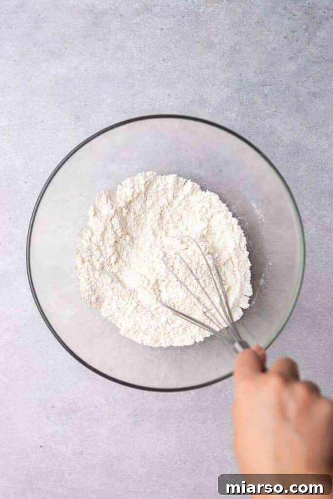 Hands whisking dry ingredients in a large bowl, preparing for small-batch biscuits.