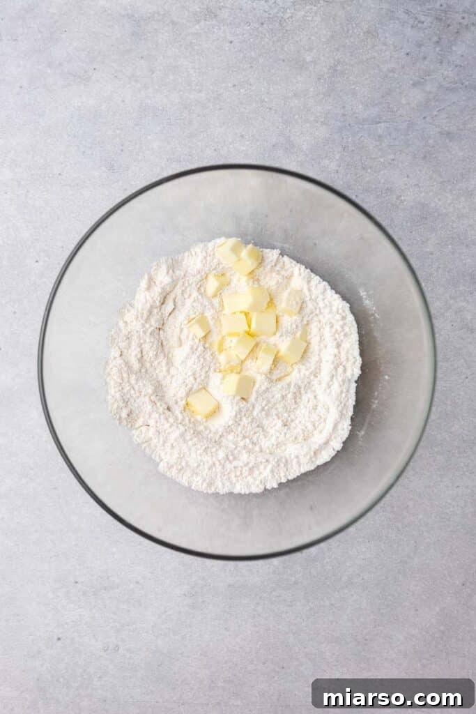 Close-up of flour and cubed cold butter in a mixing bowl before being combined.
