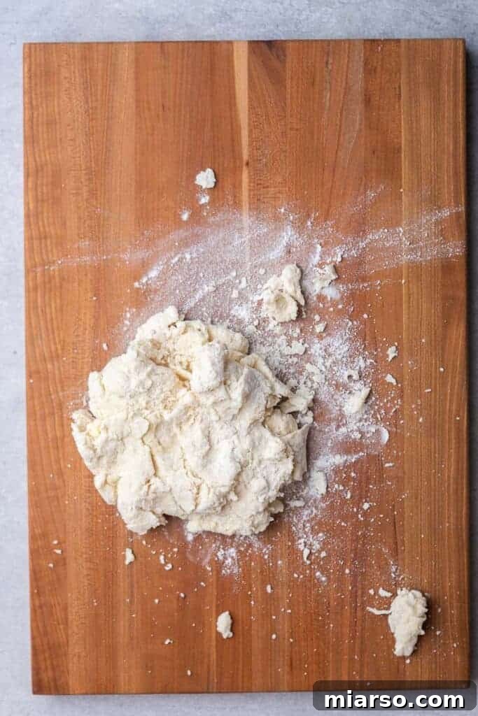 Shaggy biscuit dough forming in a bowl after buttermilk has been added, indicating minimal mixing.