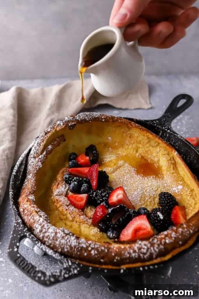 Powdered sugar and fresh berries on a warm Dutch baby pancake