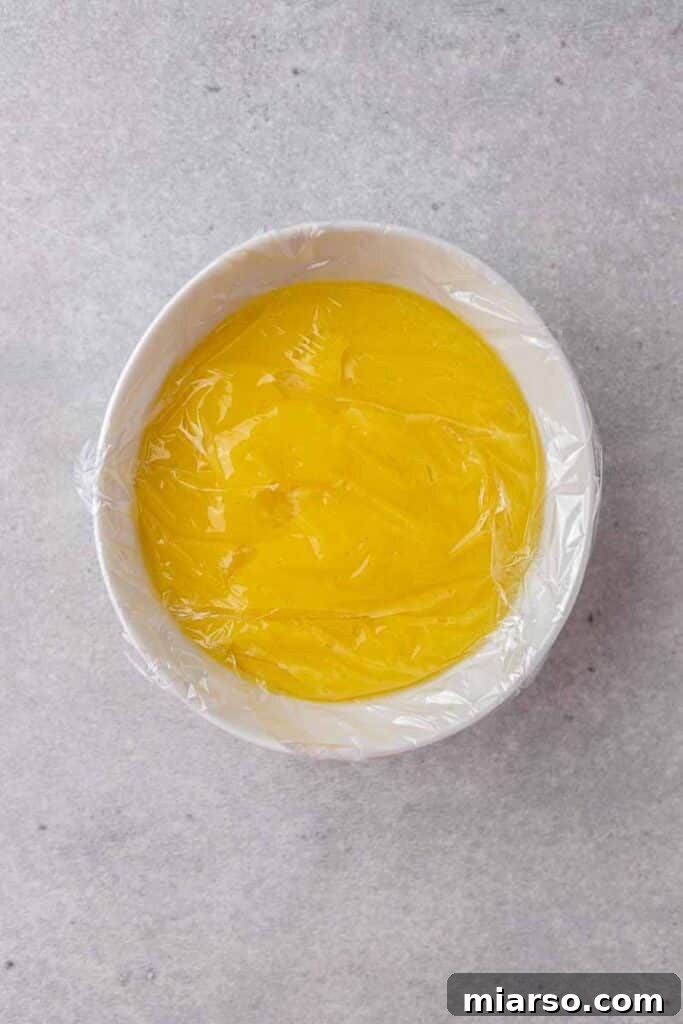 Lemon curd in a bowl with plastic wrap