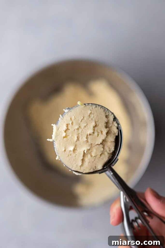 Effortless Crumbl Lemon Glazed Cookies 7 Lemon cookie dough being scooped with a cookie scoop.