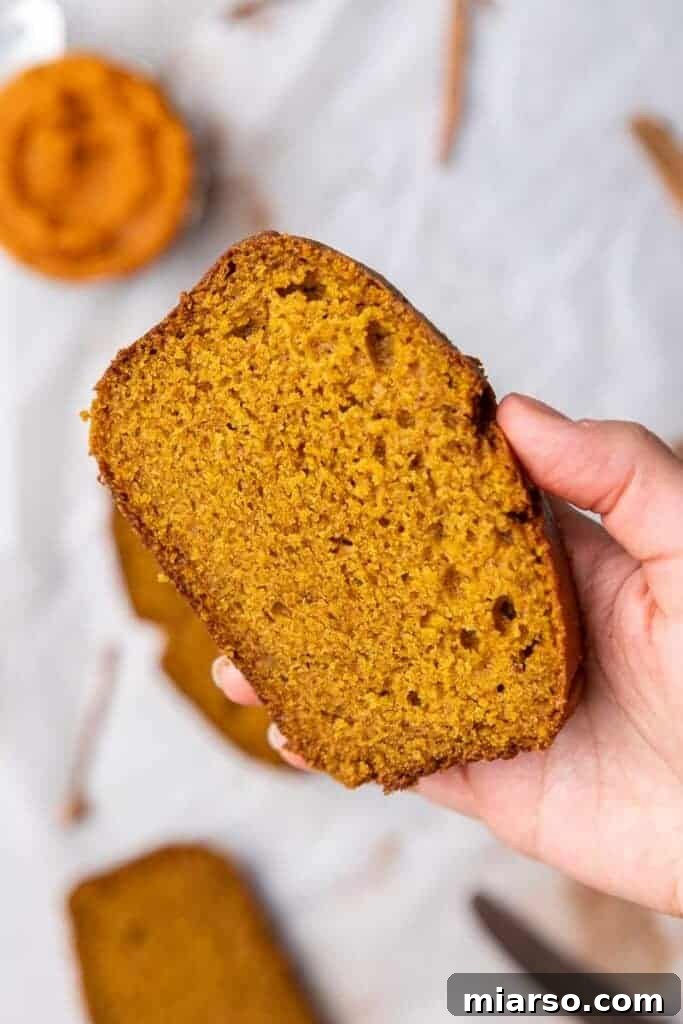 Hand holding a slice of moist pumpkin quick bread