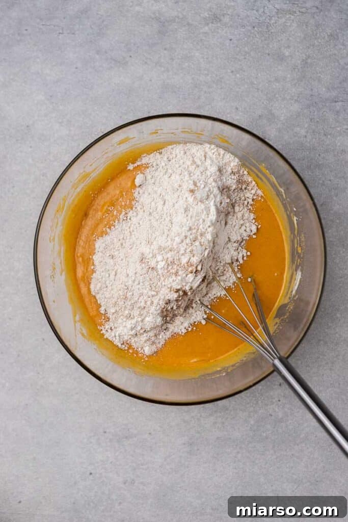 Combining wet ingredients with flour for pumpkin bread