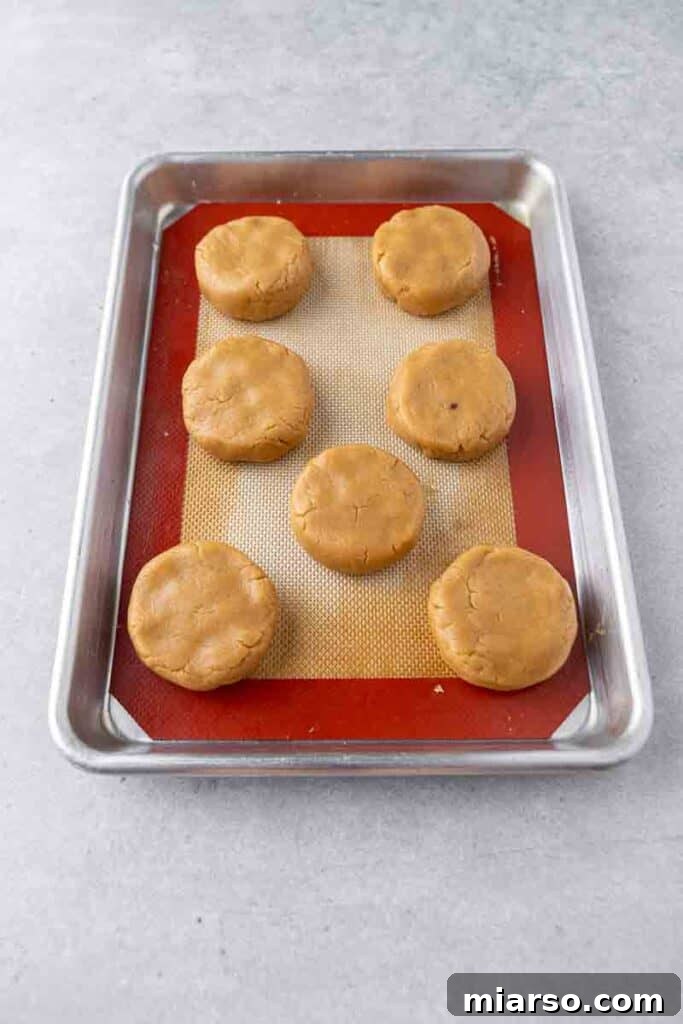 Soft Baked Peanut Butter and Jelly Cookies 8 Thick peanut butter cookie dough discs on a baking sheet, ready for the oven.