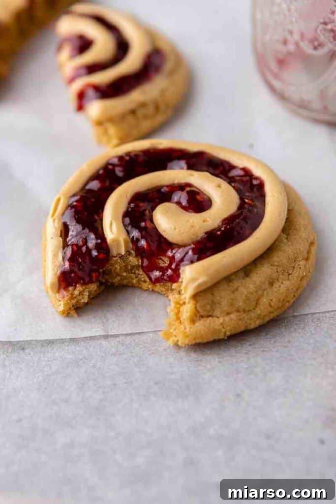 Soft Baked Peanut Butter and Jelly Cookies 9 A finished peanut butter and jelly cookie with a bite taken out, showing the soft interior.