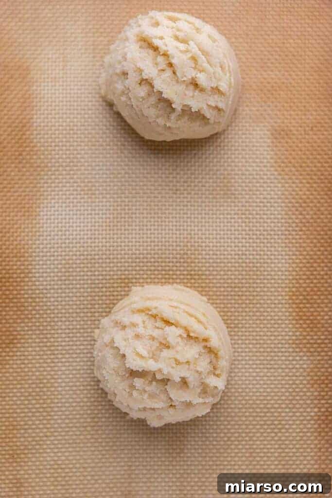 Raw cookie dough balls flattened on baking sheet