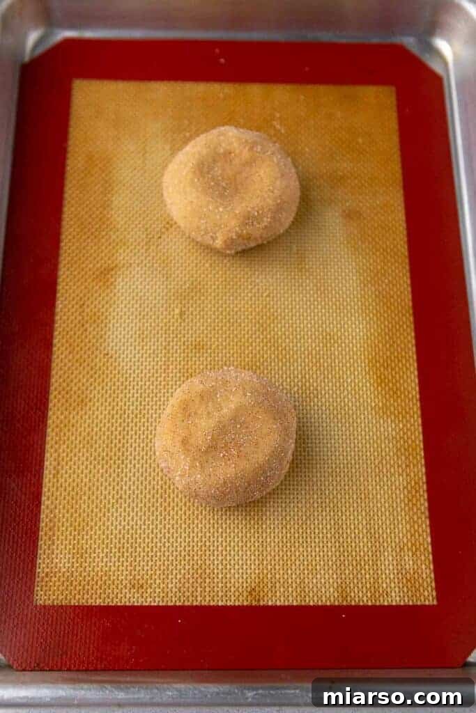 Cookie dough balls coated in cinnamon sugar on a baking sheet