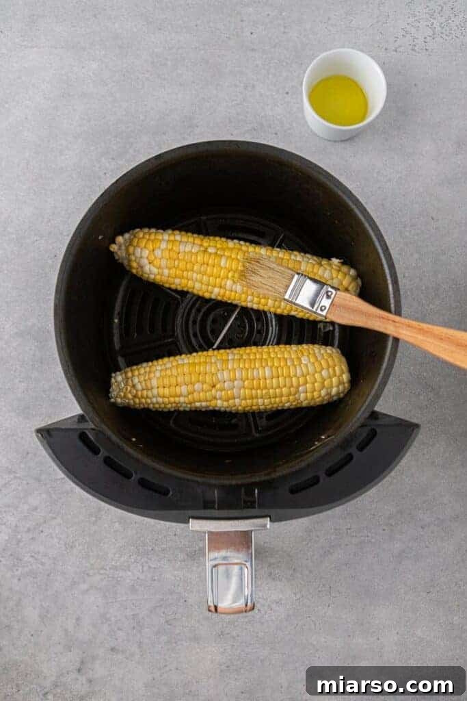 Air Fryer Golden Corn Cobs 4 Brushing fresh corn with olive oil before air frying