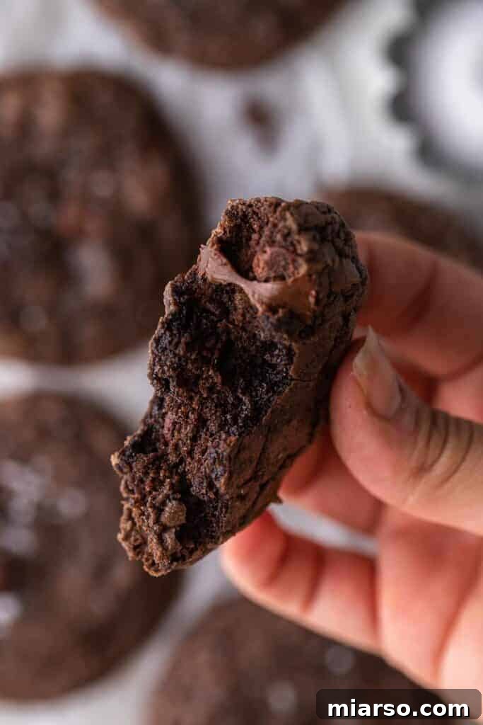 Crumbl's Rich Brownie Batter Indulgence 13 Hand holding two warm, chocolate brownie batter cookies