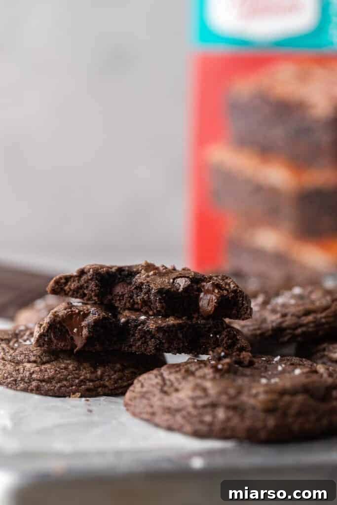 Crumbl's Rich Brownie Batter Indulgence 14 A delectable brownie mix cookie broken in half, revealing its soft, fudgy interior.