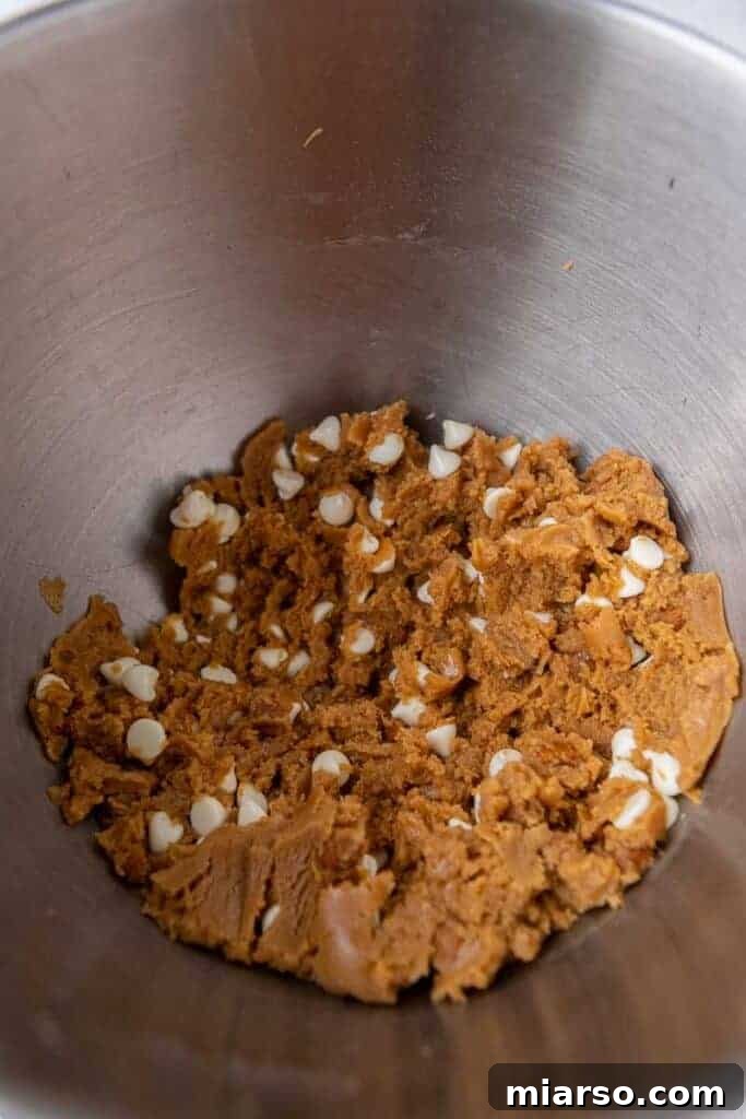 The Best Crumbl Biscoff White Chip Cookies Recipe 9 A close-up shot of the ready Crumbl biscoff cookie dough, speckled with crushed Biscoff cookies and white chocolate chips.