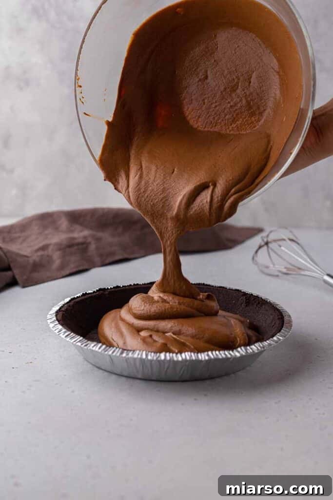 Pouring the creamy chocolate pie filling into a pre-made Oreo crust.