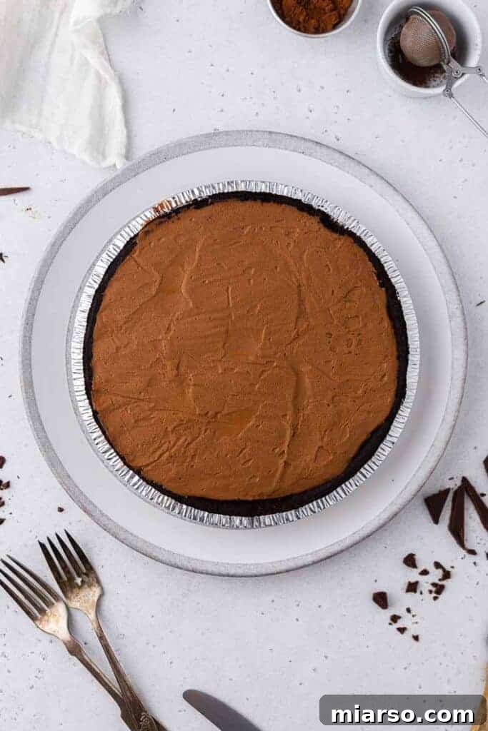 A fully assembled no-bake chocolate pie, chilling in the refrigerator to set.