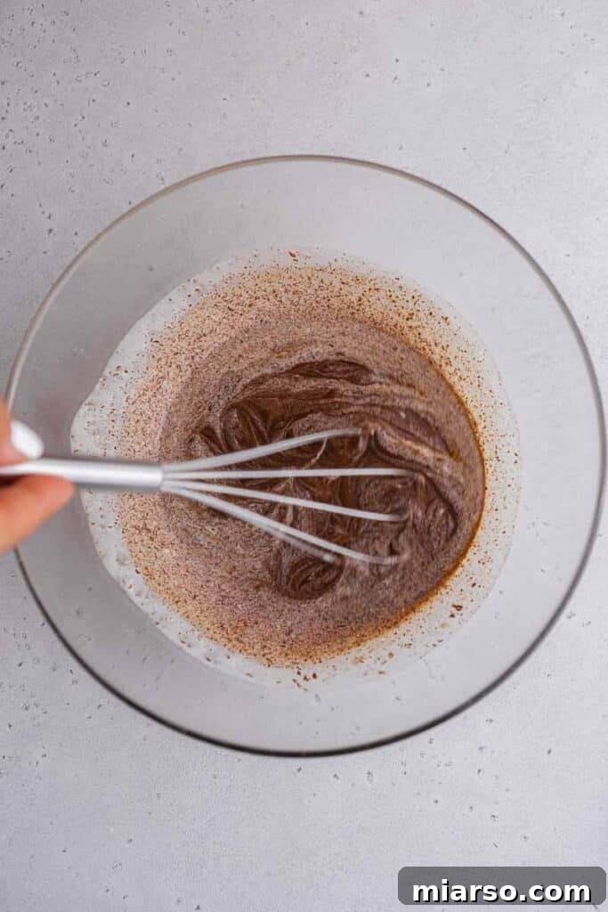 Whisking the chocolate and heavy cream together to create a smooth, glossy ganache.