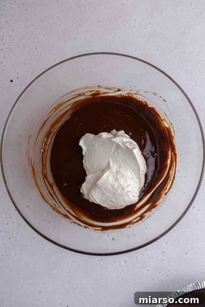 Light and airy whipped cream being folded into the rich chocolate ganache mixture.