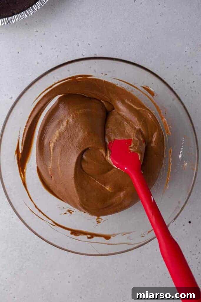 A spatula gently folding the whipped cream into the chocolate ganache to create a mousse.