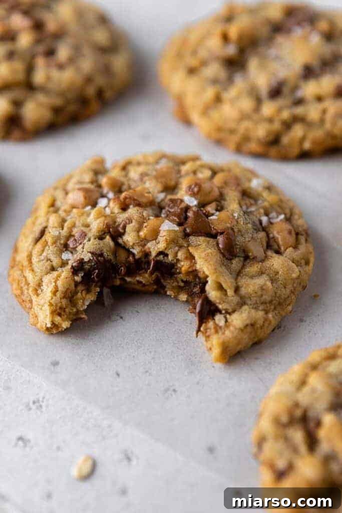 A Crumbl Mom's Recipe Cookie with a bite taken out, revealing its soft interior and melted chips.