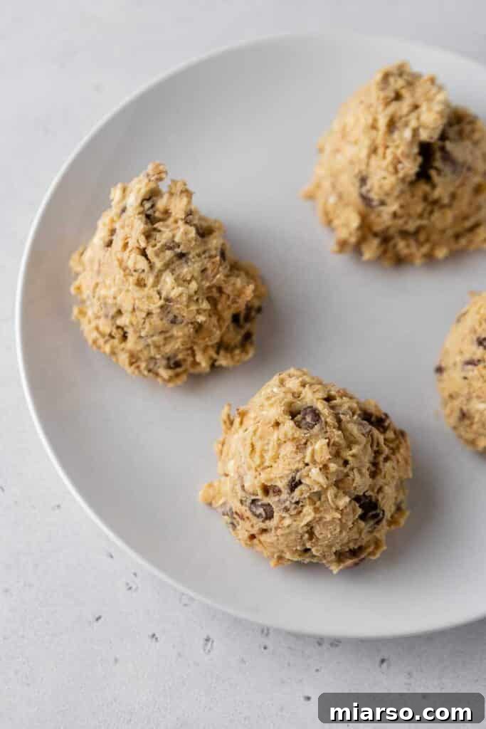 Scooped oatmeal cookie dough balls arranged on a baking sheet.