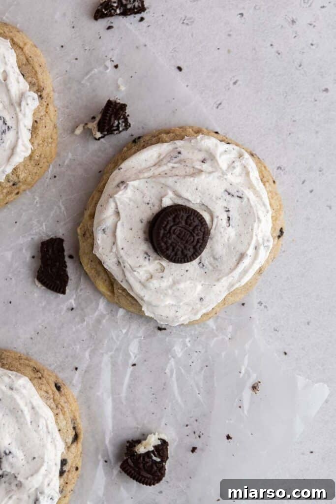 Overhead shot of freshly frosted Crumbl cookies and cream cookies with mini Oreos