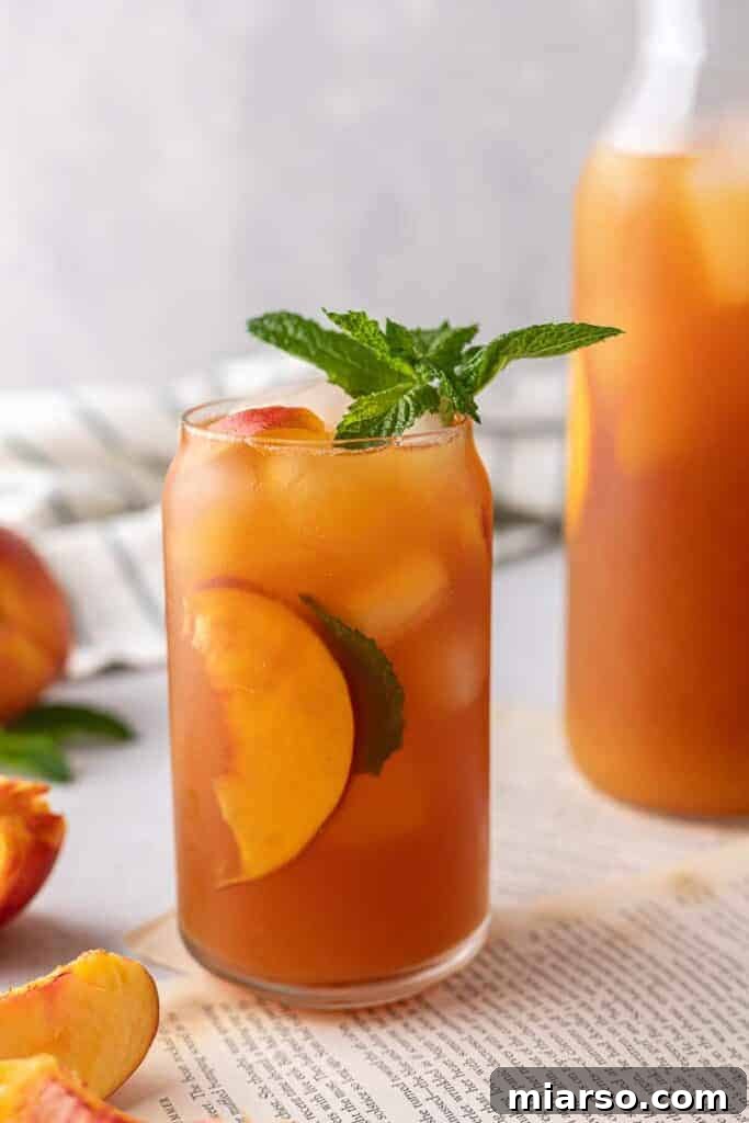 Refreshing homemade peach iced tea served over ice with fresh peach slices, perfect for summer.